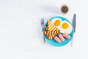 Leckeres Frühstück mit Eiern, Würstchen, Toast und einer Tasse Kaffee. amerikanisches Frühstück. Ansicht von oben foto