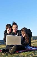 Gruppe von Teenagern, die im Freien am Laptop arbeiten foto