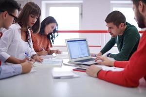 studentengruppe, die gemeinsam an einem schulprojekt auf einem tablet-computer an einer modernen universität arbeitet foto