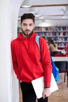 der Schüler benutzt einen Laptop und eine Schulbibliothek foto