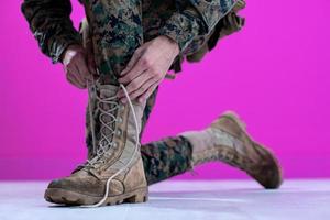 Soldat, der die Schnürsenkel an seinen Stiefeln bindet foto