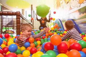 junge Mutter spielt mit Kindern im Pool mit bunten Bällen foto