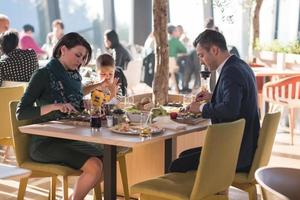 junge eltern, die mit ihren kindern die mittagessen genießen foto