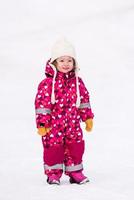 kleines Mädchen, das sich am verschneiten Wintertag amüsiert foto