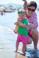 Mama und Baby am Strand haben Spaß foto