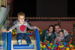 eltern und kinder spielen im pool mit bunten kugeln foto