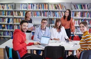 studentengruppe, die gemeinsam an einem schulprojekt auf einem tablet-computer an einer modernen universität arbeitet foto