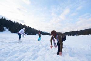 glückliche Familie, die im Winter zusammen im Schnee spielt foto