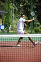 junger Mann spielt Tennis im Freien foto