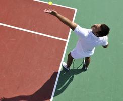 junger Mann spielt Tennis im Freien foto