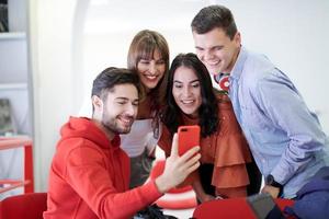 gruppe multiethnischer teenager, die in der schule ein selfie machender schüler benutzt ein notizbuch und eine schulbibliothek foto