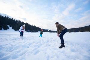 glückliche Familie, die im Winter zusammen im Schnee spielt foto