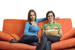 freundinnen, die popcorn essen und zu hause fernsehen foto