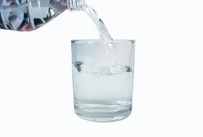 Gießen von Wasser in ein Glas auf weißem Hintergrund foto