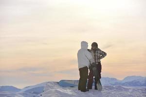 Snowboarderpaar auf dem Gipfel des Berges foto