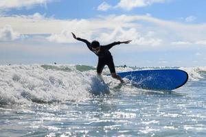 Junge, neuer Surfschüler, verliert sein Körpergleichgewicht und fällt während des Unterrichts vom Surfbrett ins Wasser. foto