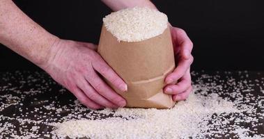 Weißer Reis in einer Tüte wird auf den Tisch gegossen foto