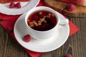 roter Himbeertee mit Fruchtstückchen und Beeren foto