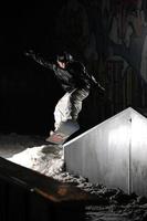 Freestyle-Snowboarder springen nachts in die Luft foto