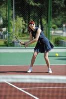 junge frau spielt tennisspiel im freien foto