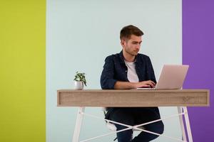 lächelnder junger freiberufler mit laptop, der online von zu hause aus arbeitet foto