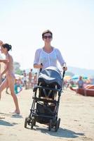 Mutter am Strand spazieren und Kinderwagen schieben foto