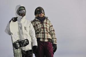 Snowboarderpaar auf dem Gipfel des Berges foto