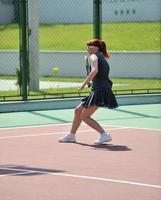 junge frau spielt tennisspiel im freien foto