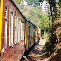 Spielzeugeisenbahn, die sich auf Berghängen bewegt, schöne Aussicht, ein Seitenberg, ein Seitental, das sich auf der Eisenbahn zum Hügel bewegt, inmitten grüner Naturwälder. spielzeugeisenbahn von kalka nach shimla in indien, indischer zug foto