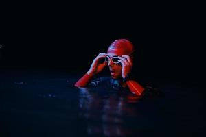 Authentischer Triathlet-Schwimmer, der während des harten Trainings im nächtlichen Neon-Gel-Licht eine Pause macht foto