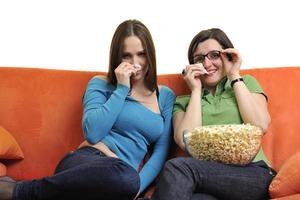 freundinnen, die popcorn essen und zu hause fernsehen foto