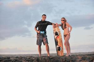 Surf-Paar posiert am Strand bei Sonnenuntergang foto