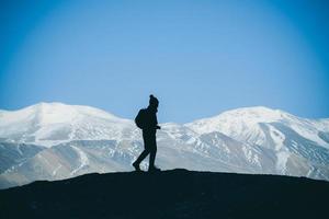 silhouette der wandererin steht auf dem felsen in den wunderschönen bergen blick auf den schneebedeckten tso moriri see in leh ladakh indien, erfolgskonzept foto