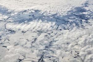 luftaufnahme über wolkenoberseite zu schneebedeckten flüssen, feldern und straßen, winterfrische frostige luft foto