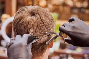 männlicher haarschnitt im friseursalon nahaufnahme, kunde bekommt haarschnitt vom friseur mit kamm und schere foto