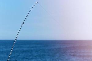 Angelrute vor blauem Ozean- oder Meereshintergrund, Kopierraum. Warten auf den größten Fang. meditativer Entspannungssport. foto