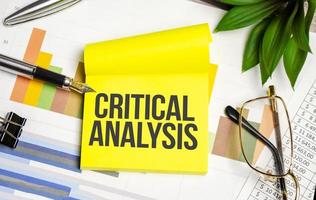 Kritischer Analysetext auf gelbem Papier mit Stift und Brille foto