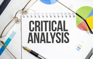 Kritischer Analysetext auf weißem Notizbuch mit Taschenrechner und Stift foto
