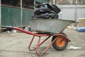 Gartenwagen mit schwarzen Taschen im Inneren. Säuberung des Territoriums. Transport von Müll. foto