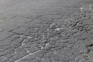 Gruben und Risse auf dem Asphalt der Straße foto