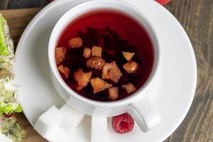 roter Himbeertee mit Fruchtstückchen und Beeren foto