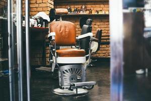 Stilvoller Vintage-Friseurstuhl im Backsteinmauer-Interieur. Friseursalon-Thema. Friseursessel. moderner friseur und friseursalon, friseursalon für herren. foto