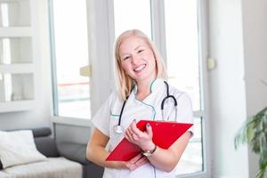 Ärztin, die in ihrem Büro steht, füllt die Aufzeichnungen über die Medikamentenhistorie auf. Arzt bei der Arbeit, Portrait-Shooting. medizin- und gesundheitskonzept foto