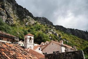 dächer von häusern und hohen bergen in kotor, montenegro foto