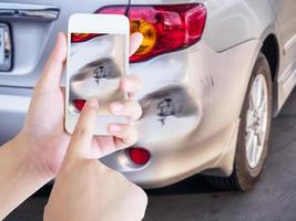 Frau, die ein mobiles Smartphone verwendet, um ein Foto eines Autounfalls zu machen, der für die Versicherung beschädigt wurde