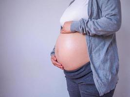schwangere Frau, die ihren Bauch aus nächster Nähe berührt foto