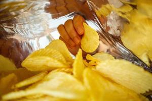 Halten Sie Kartoffelchips in der Hand im Snackfolienbeutel foto