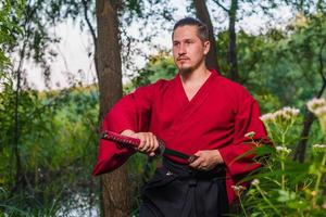 Mann in ethnischer Samurai japanischer Kleidungsuniform mit Katana-Schwert