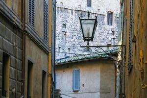 Laterne zwischen mittelalterlichen Häusern auf der Straße in Siena foto