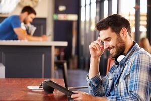 Mann mit digitaler Tablette in einem Café